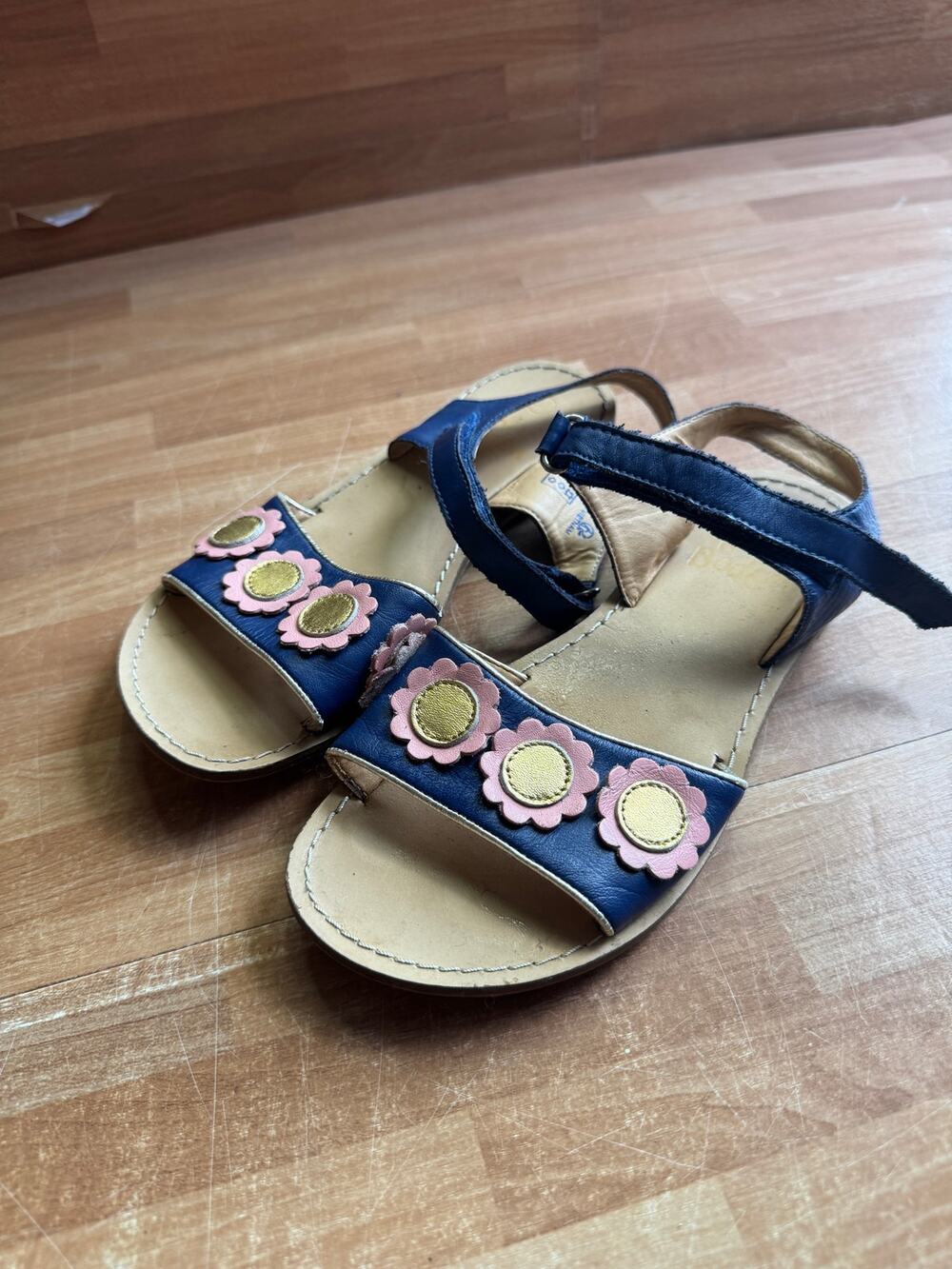 Boden sandals featuring navy leather and pink/gold flower appliqués.